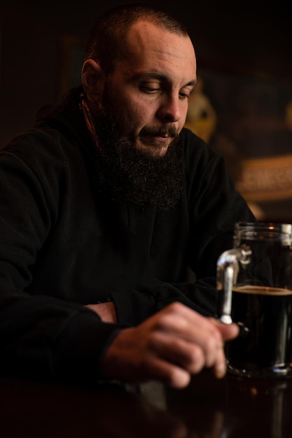 Bearded man holds glass of beer while sitting in pub Beer time Alcohol drinks