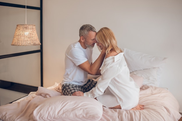 Bearded man hugging a blonde woman and looking romantic