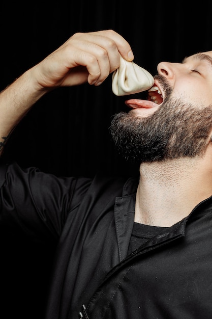 The bearded man is emotionally eating khinkali. The national Georgian dish khinkali. Concept of advertising photo of khinkali.