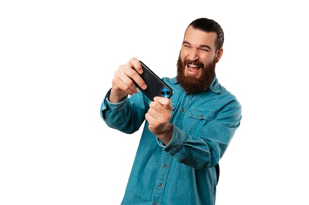 Bearded man is having fun and a good time while playing with his phone