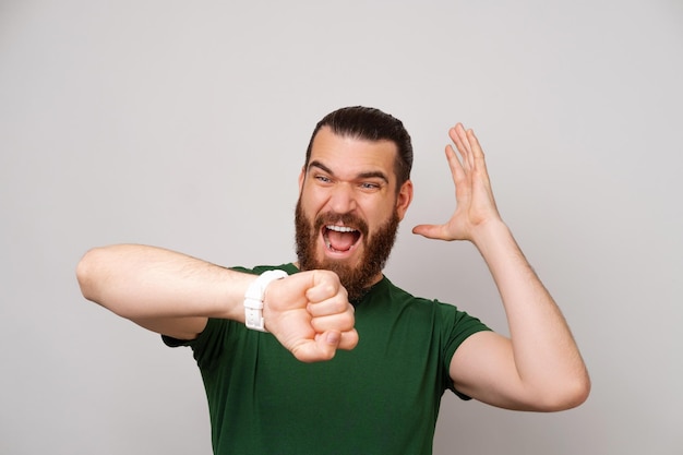 Bearded man is upset because he is late while looking at the watch he has got