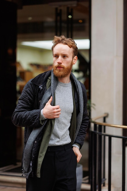 Bearded man in a jacket and scarf walks down the street