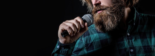 Bearded man in karaoke sings a song into a microphone Male attends karaoke Man with a beard holding a microphone and singing