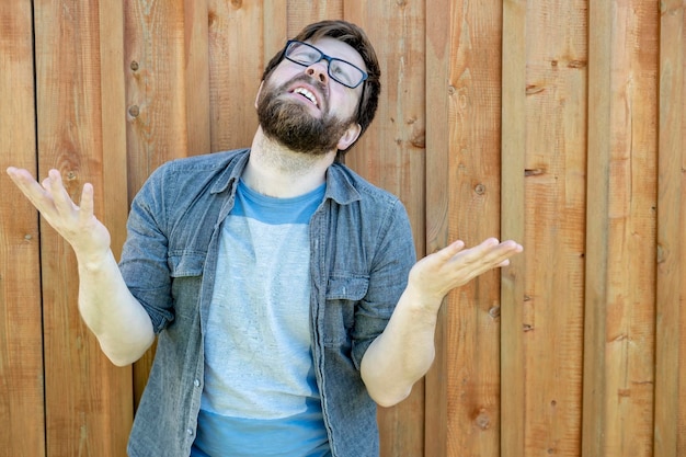 A bearded man raises his palms and head up and makes a moan Emotions of despair and problems