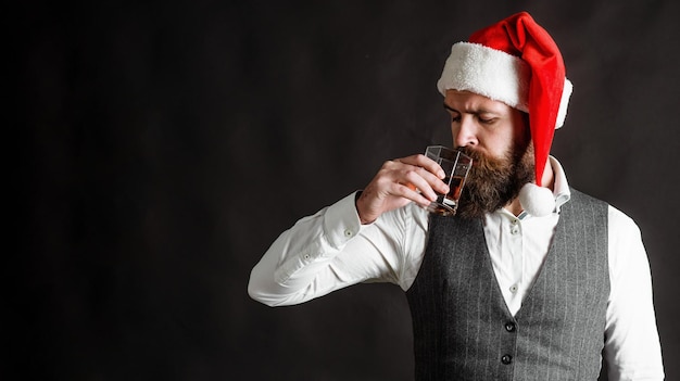 Bearded man in santa hat drinks whisky alcohol christmas or new year party