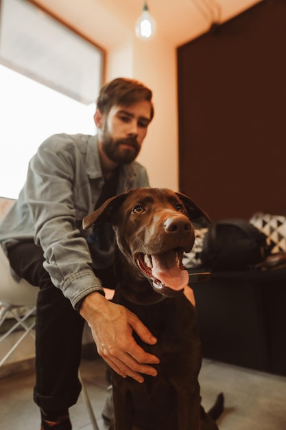 Bearded man sitting in cozy cafe with dog Portrait of a dog indoors playing with a pet