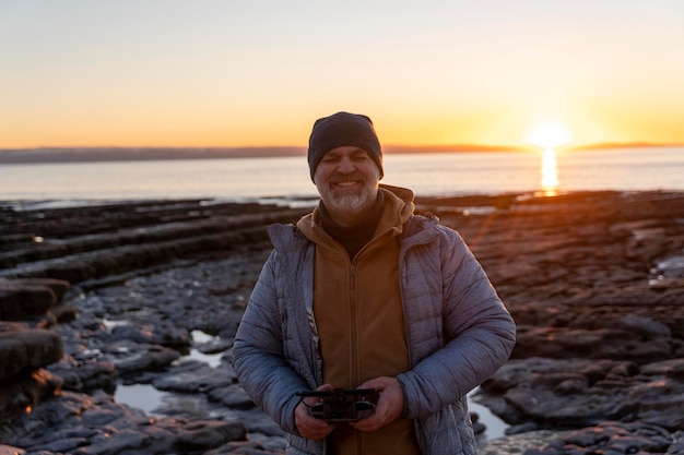 Bearded man using a drone with remote controller making photos and videos having fun