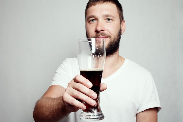 Bearded man in a white T-shirt holding a pint glass