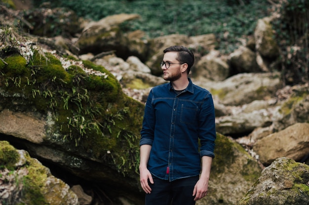 bearded man in wild forest with stones around