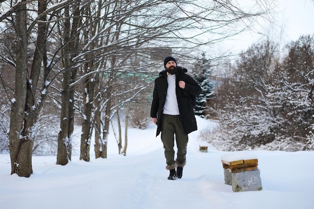 Bearded man in the winter woods. Attractive happy young man with beard walk in the park.