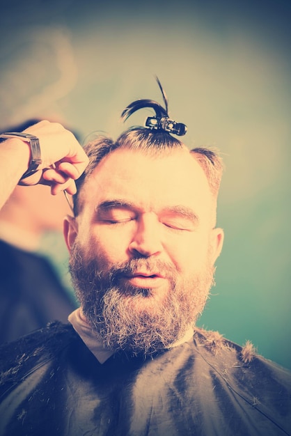 A bearded man with a clip on the head in a hairdressing salon