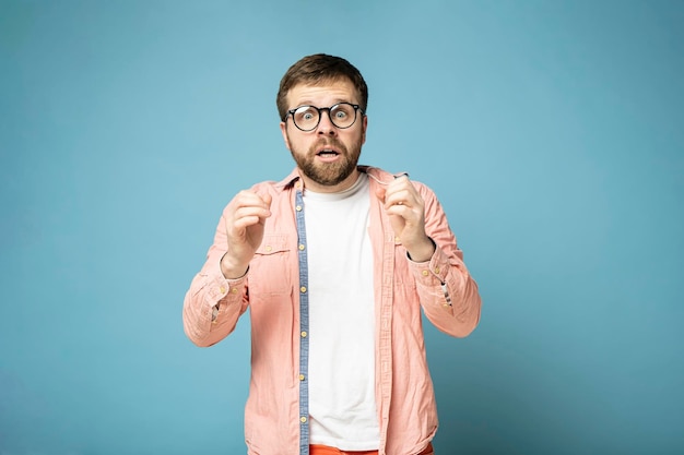 Bearded man with glasses excited by an unexpected surprise he emotionally raises hands