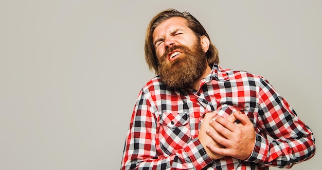 Bearded man with heartache holding hand on chest heart attack or stroke health care concept