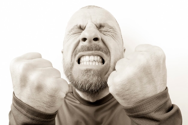 Bearded man with strong emotions and with clenched fists closeup on white background. aggression and nervousness. stress and insanity