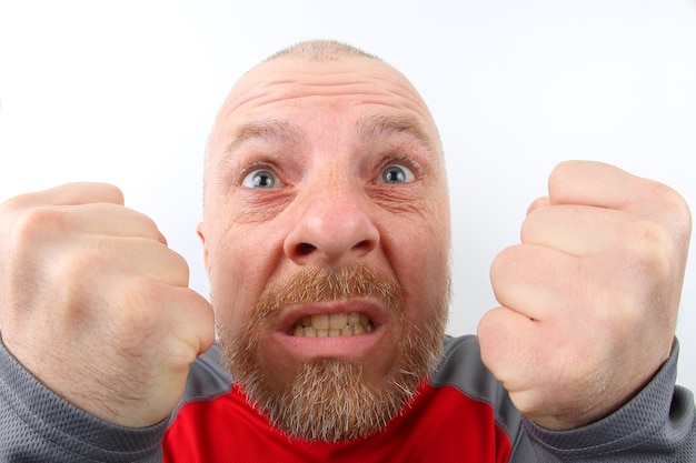 Bearded man with strong emotions and with clenched fists closeup on white