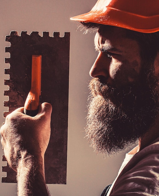 Bearded man worker, beard, building helmet, hard hat. Plastering tools. Builders in hard hat, helmet.