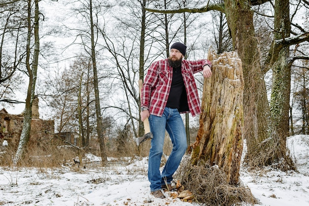 Bearded maniac with an ax walking on a snowy road