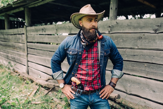 beared man with hat and a gun