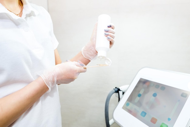 Beautician applies cooling gel on wooden spatula before laser hair removal