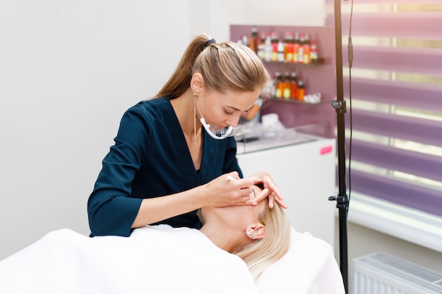 Beautician applies marking on eyebrows. 