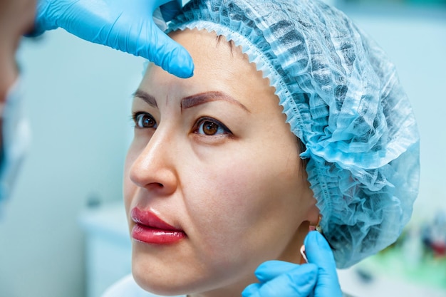 Beautician, applies the markup on the eyebrows for permanent makeup eyebrows. Eyebrow tattoo and lips