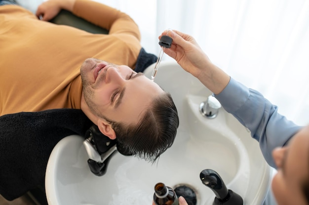 Beautician applying hair serum on mans head