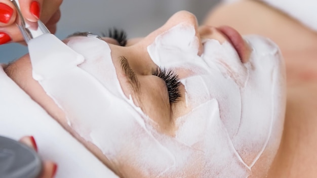 Beautician cosmetologist applying face peeling beauty mask Spa salon