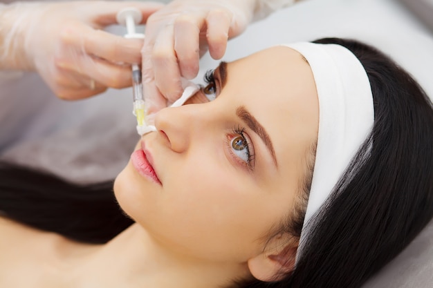 Beautician doing beauty injection to woman lips