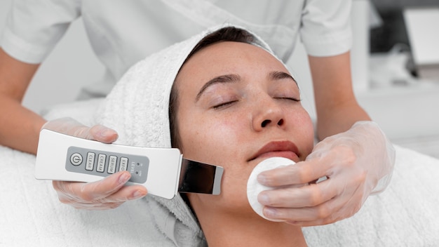 Photo beautician doing face beauty routine for female client