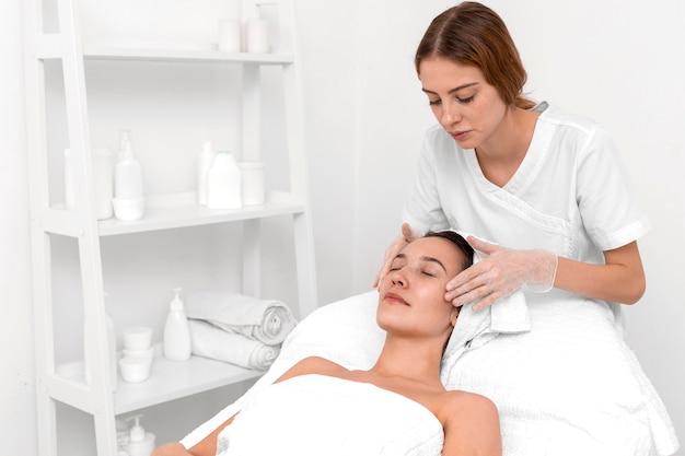 Photo beautician doing face beauty routine for female client