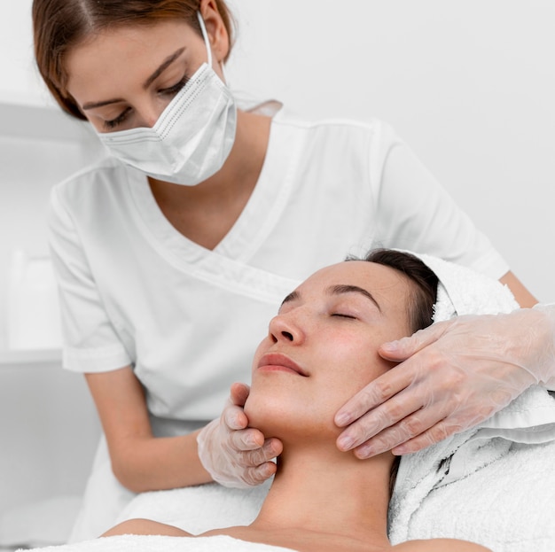 Photo beautician doing face beauty routine for female client