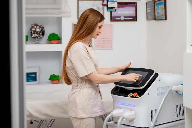 Beautician holding ultrasound device for face and skin lifting procedure and hair removal Young woman cosmetologist using modern cosmetology equipment in clinic