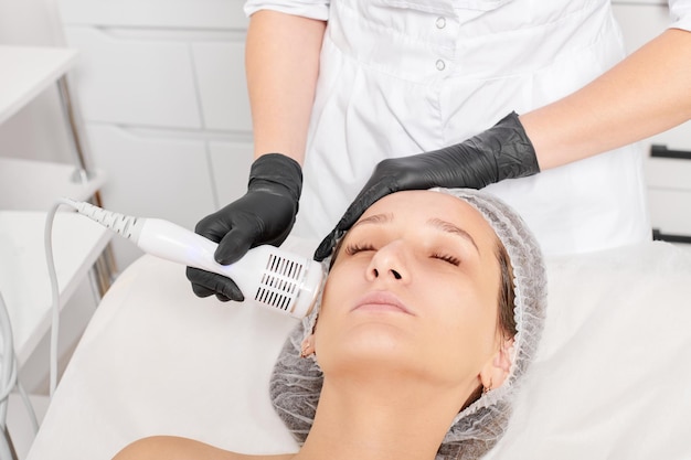 Beautician makes cryotherapy for rejuvenation woman face anti aging procedure in salon