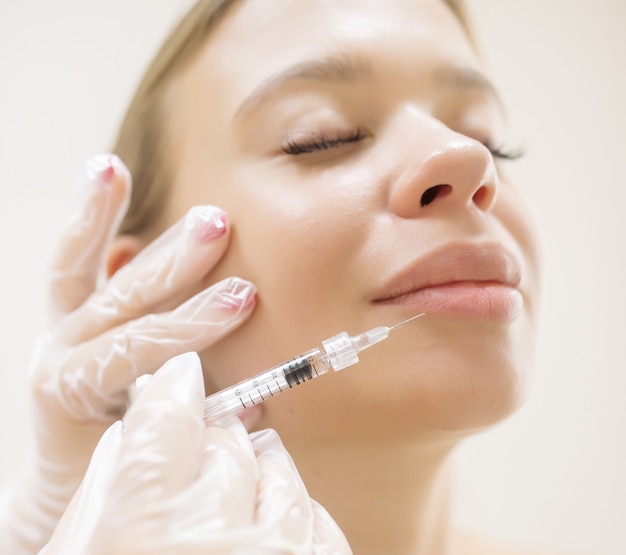 The beautician makes the patient augmentation of the lips with the help of injections of the hyaluronic acid filler