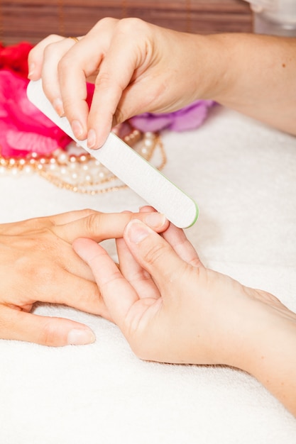 The beautician polish the client's nails before putting nail polish