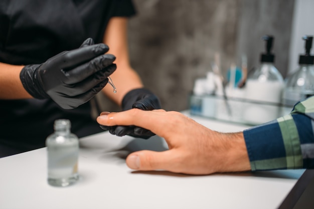 Beautician polishing nails to male client in salon