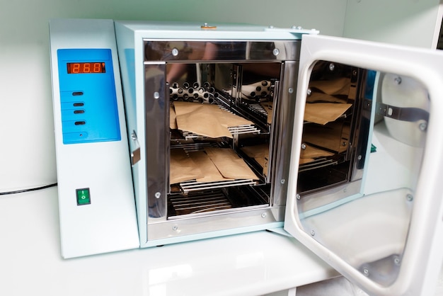 Beautician in protective gloves close the door of the machine for disinfection of tools before the depilation procedure