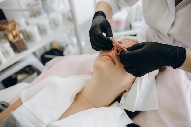 Beautician removes a clay mask from the face of a young woman in the Spa salon Beautiful young girl at the beautician does the spa procedures