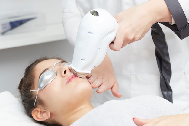 Beautician Removing Hair Of Young Woman with laser