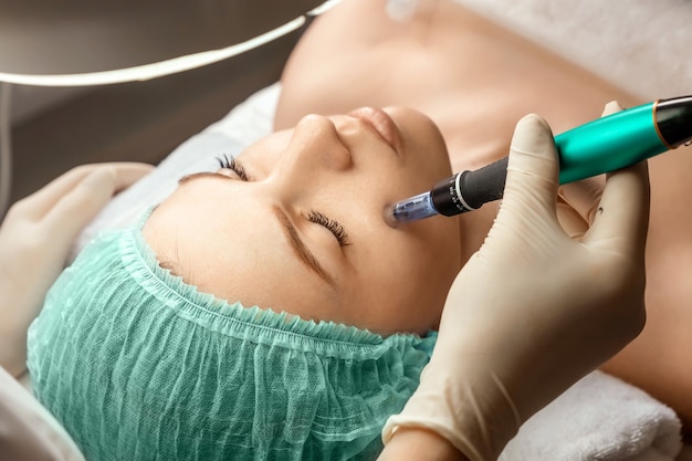 A beautician wearing medical gloves cleans the pores on the face using special equipment