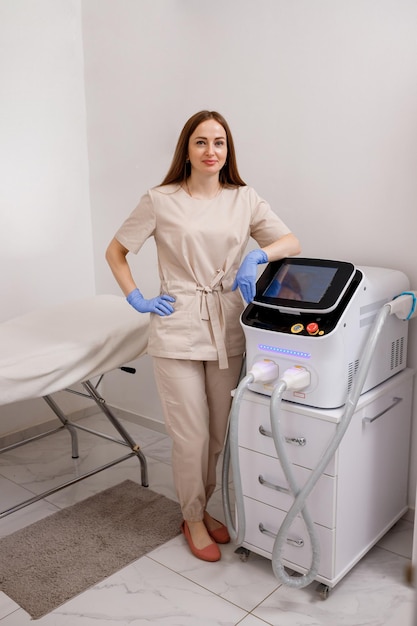 Beautician with ultrasound device for face and skin lifting procedure and hair removal Young woman cosmetologist using modern cosmetology equipment in clinic