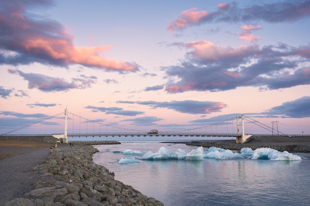 BeautifBeautiful sunset over suspension bridge on Jokulsarlon glacial river lagoon with iceberg floating in southern of Vatnajokull National Park at Iceland