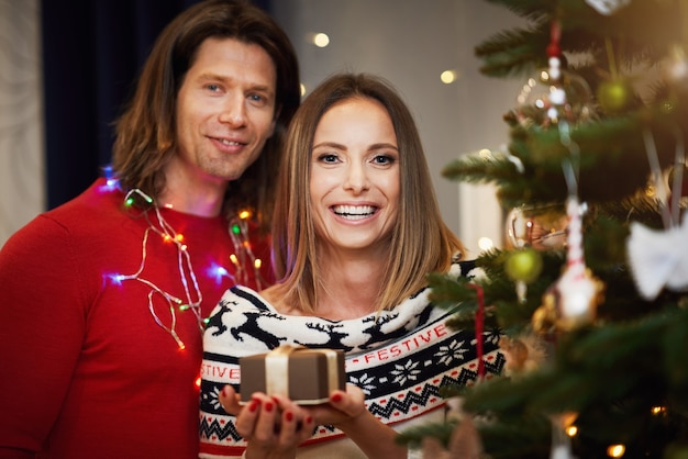 beautiful adult couple with present over Christmas tree