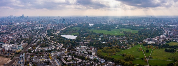 Beautiful aerial view of London with many green parks and city skyscrapers in the foreground.