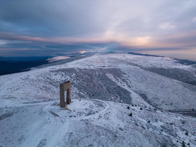 Beautiful aerial view of snow covered mountains and the Monument Arch of Liberty at the main ridge of Balkan Mountains Bulgaria in winter morning