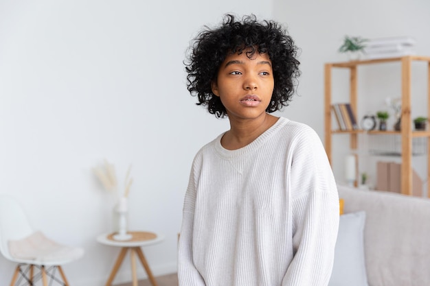 Beautiful african american girl with afro hairstyle at home indoor Young african woman with curly hair in living room Beauty ethnic people domestic life concept