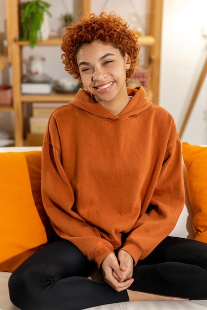 Beautiful african american girl with afro hairstyle smiling sitting on sofa at home indoor young afr