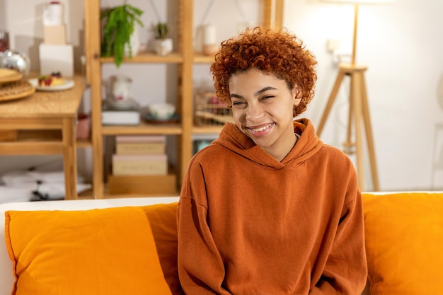 Beautiful african american girl with afro hairstyle smiling sitting on sofa at home indoor young afr