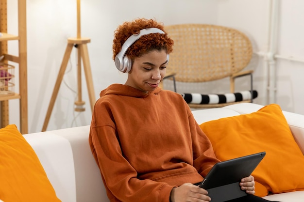 Beautiful african american girl with afro hairstyle wearing headphones smiling listening music at ho