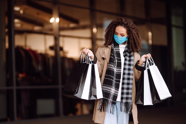 Beautiful african american woman in protective mask after shopping near the store